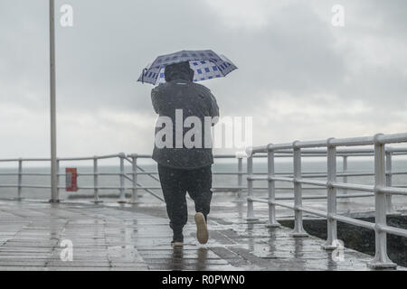 Aberystwyth, Wales, UK. 7th November, 2018.   UK Weather: People walking in the rain on a  very wet , but mild, morning in Aberystwyth. The Met Office has issued a yellow warning for rain and floods covering much of south and west wales this morning, with a further warning for more rain and gale force winds issued for the same area on Friday as well.   Photo credit: Keith Morris/ Alamy Live News Stock Photo