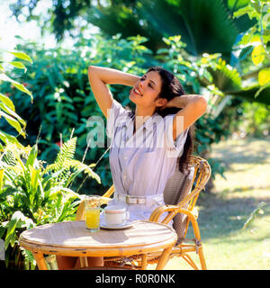 Young woman stretching in tropical garden, Guadeloupe, French West Indies, Stock Photo