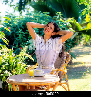 Young woman stretching in tropical garden, Guadeloupe, French West Indies, Stock Photo