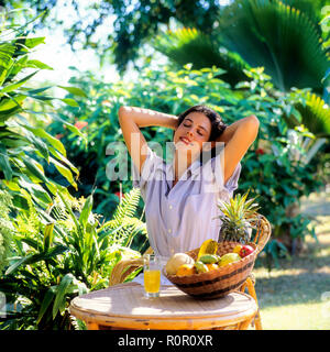 Young woman stretching in tropical garden, Guadeloupe, French West Indies, Stock Photo