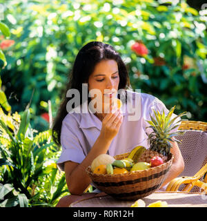 Young woman eating exotic fruits in tropical garden, Guadeloupe, French West Indies, one fit woman eating fruit Stock Photo