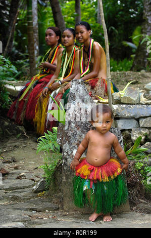 Einheimische Frauen und kleines Mädchen tragen Baströcke, Yap, Mikronesien | Traditionally dressed women with little girl wearing hula skirts, Yap, Mi Stock Photo