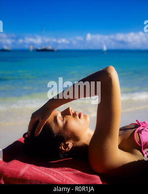 Portrait of young woman sunbathing, eyes closed, holding her head with hand, Caribbean sea, Guadeloupe, French West Indies, Stock Photo