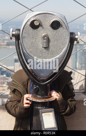 Nine year old boy using coin operated binoculars, 86th Floor observation deck, Empire State Building, New York City, United States of America. Stock Photo