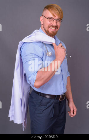 Bearded man doctor with blond hair against gray background Stock Photo