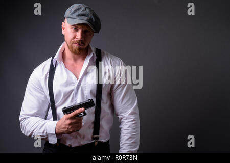 Bearded man with handgun against gray background Stock Photo