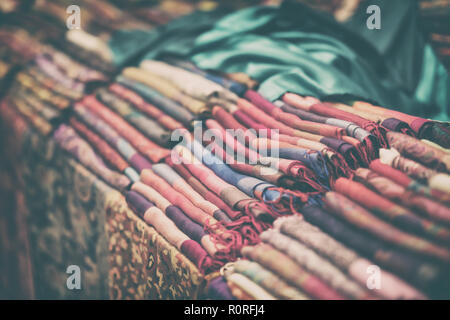 Multicolored fabric scarves, shawls, stoles, real store shelf, vintage background Stock Photo