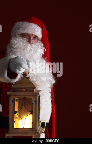 Santa Claus holding retro style lantern , dark red background Stock Photo