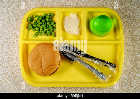 Elementary school lunch cheeseburger with mashed potatoes gelatin and green peas on portion tray Stock Photo