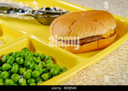 Elementary school lunch cheeseburger with mashed potatoes gelatin and green peas on portion tray Stock Photo