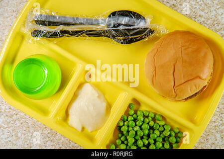 Elementary school lunch cheeseburger with mashed potatoes gelatin and green peas on portion tray Stock Photo