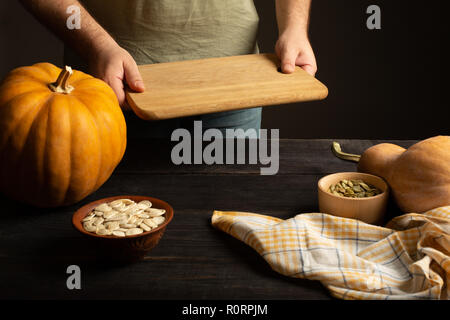 Cutting board in male hands. Preparation for cutting pumpkin. Stock Photo