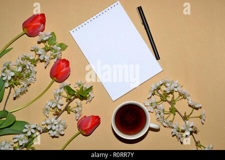 Open Notepad for writing framed with tulips and white flowers, and a Cup of tea. Stock Photo