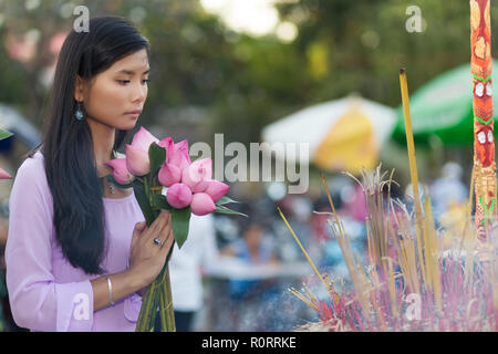 Vietnamese woman praying in temple, holding lotus flower buds bunch, Vietnam Stock Photo