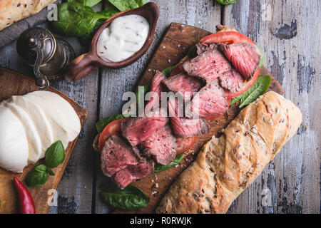 Steak sandwich, sliced roast beef, cheese,spinach leaves,tomato Stock Photo