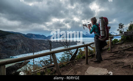 Scout woman with her backpack taking photograph of the Grey glacier in Torres del Paine National Park in Chilean Patagonia Stock Photo