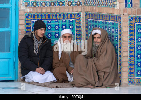 Three Men Sitting In An Alcove At The Shrine Of Hazrat Ali, also called the Blue Mosque, Mazar-e Sharif, Afghanistan Stock Photo