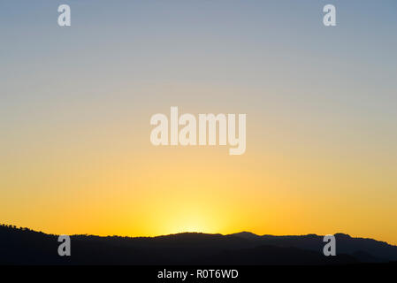Orange sun setting behind the mountains Stock Photo