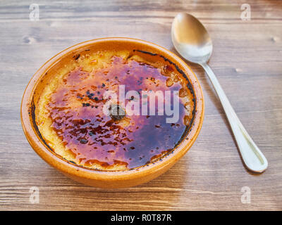 Crema Catalana or Creme Brulee in rustic bowl, typical taberna or bistro presentation with a cinnamon stick in the middle. Stock Photo