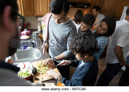 Latinx multi-generation family cooking, cutting avocados in kitchen