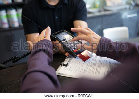 Close up woman paying, using credit card reader at gym front desk