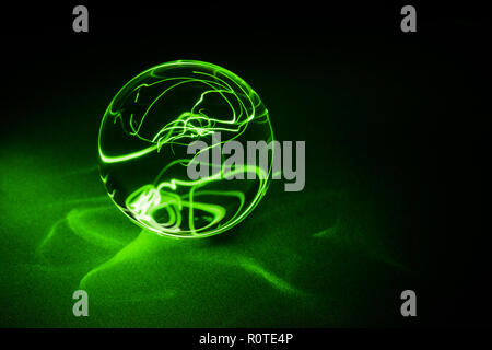Transparent Crystal ball on black with green light, close up. Stock Photo