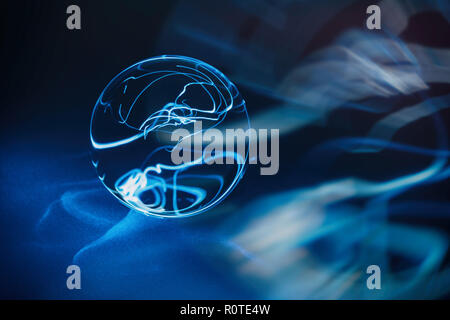 Transparent Crystal ball on black with blue light, close up. Stock Photo