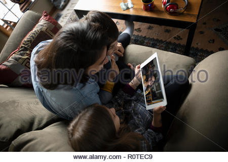 Latinx family video chatting with digital tablet on sofa
