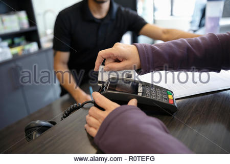 Close up woman paying, using credit card swiper at gym front desk