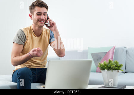 Modern user. Pleasant concentrated handsome man sitting in the armchair and resting while using cell phone Stock Photo