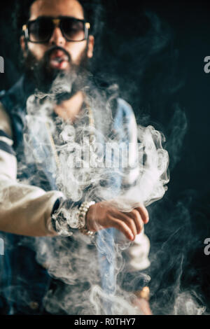 Young man with beard throwing a cloud of steam. Black background. Vaping an electronic cigarette with a lot of smoke Stock Photo