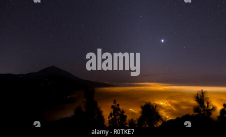 Lights of Santa Cruz shining though clouds at night on Tenerife in the Canary Islands Stock Photo