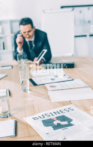 mature businessman with tablet leaning on table at conference hall Stock Photo