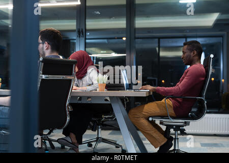 Successful business people are using a computer and smiling while working in office late at night Stock Photo