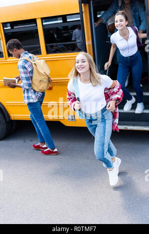 smiling multiethnic teen scholars running out school bus Stock Photo