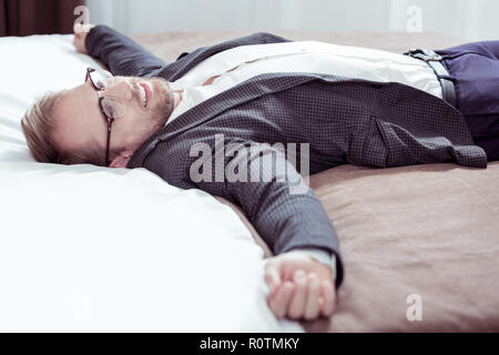 Stylish bearded businessman lying on nice bog hotel bed after long day Stock Photo