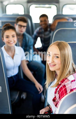 group of teen scholars riding school bus and looking at camera Stock Photo