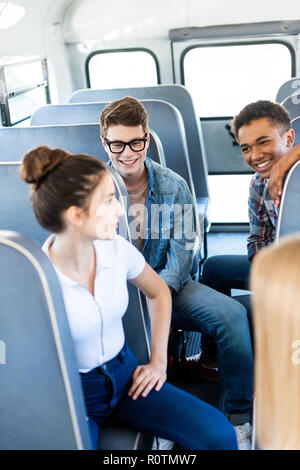 group of teen scholars riding school bus and chatting Stock Photo