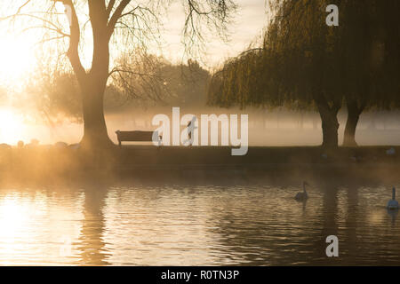 man in hat running early morning sun seen through mist on the Avon in Winter Stock Photo