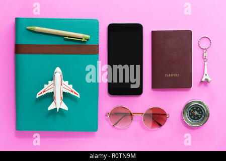 Travel concept. Closeup of mobile, passport, compass, sunglasses, airplane model and notebook on pink background. Vacation and holidays. Stock Photo