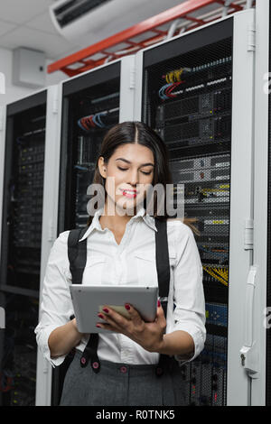 Technician apecialist woman using laptop while analyzing server in server room Stock Photo