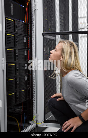 Technician apecialist woman using laptop while analyzing server in server room Stock Photo