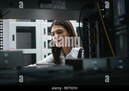 Technician apecialist woman using laptop while analyzing server in server room Stock Photo