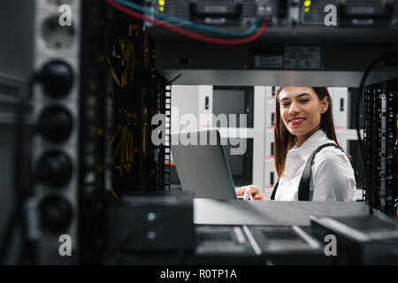 Technician apecialist woman using laptop while analyzing server in server room Stock Photo
