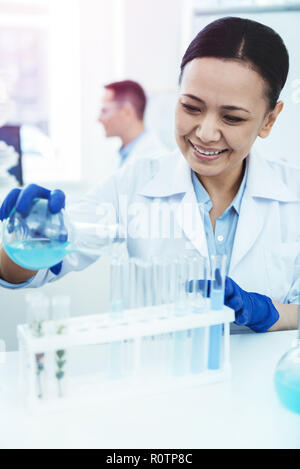 Happy nice woman pouring liquid in test tubes Stock Photo
