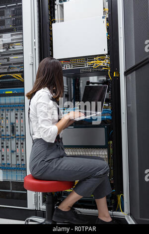 Technician apecialist woman using laptop while analyzing server in server room Stock Photo