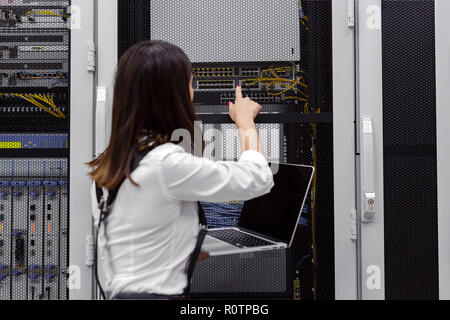 Technician apecialist woman using laptop while analyzing server in server room Stock Photo