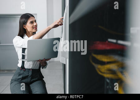 Technician apecialist woman using laptop while analyzing server in server room Stock Photo