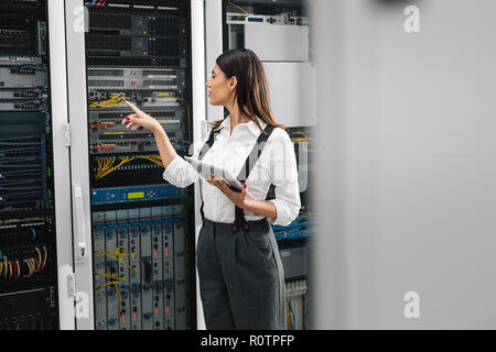 Technician apecialist woman using laptop while analyzing server in server room Stock Photo