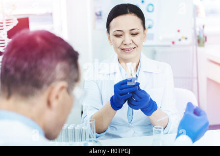 Cheerful nice woman holding a test tube Stock Photo